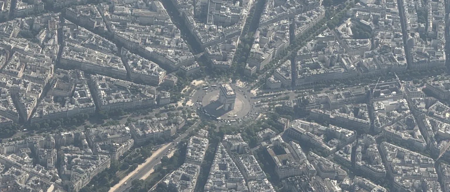 An aerial view of a city with a triumphal arch at the centre of a star of radiating avenues.